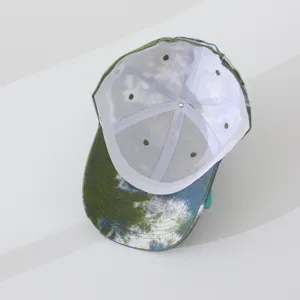Tie-dye baseball cap interior detail view, showing white lining, breathable eyelets, and fine stitching.