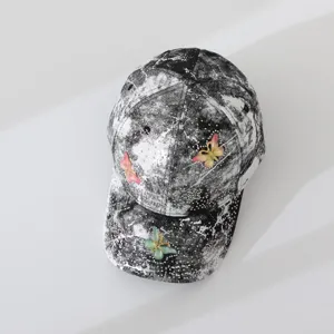 Detail view of a black and white tie-dye baseball cap with rhinestones and cute butterflies.