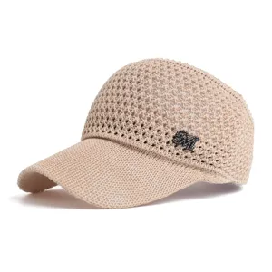 Detailed view of the beige knitted empty-top sun visor hat with rhinestone letter accent.