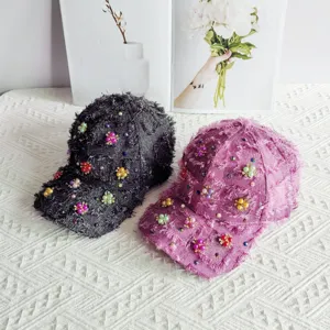 Primo piano di eleganti berretti da baseball in tweed con perle e fiori di cristallo fatti a mano.