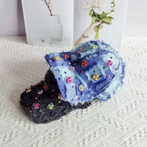 Primo piano del berretto da baseball in jeans patchwork fatto a mano con perle, strass e nappe.