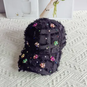 Primo piano del berretto da baseball in tweed nero con fiori di perle e strass fatti a mano.