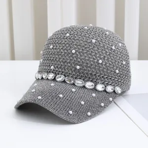 Detailaufnahme einer grauen Strick-Baseballkappe, verziert mit Perlen und funkelnden Strasssteinen.