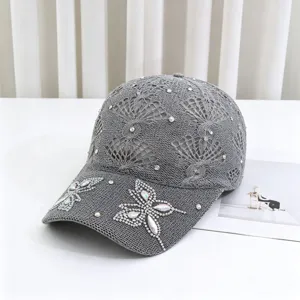 Dettaglio di berretto da baseball in maglia traforata grigia con farfalla di strass.