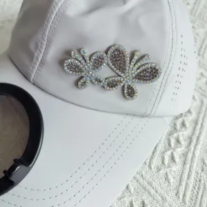 Detailed view of a white quick-drying baseball cap with sparkling rhinestone butterfly decorations.