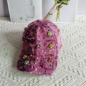 Primo piano sui dettagli del cappellino da baseball in tweed con fiori di perle fatte a mano.