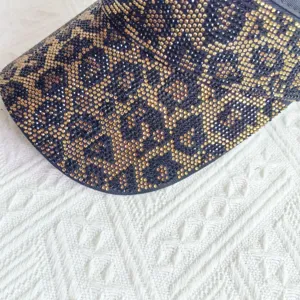 Primer plano detallado de la elegante visera solar con estampado leopardo y strass brillante.