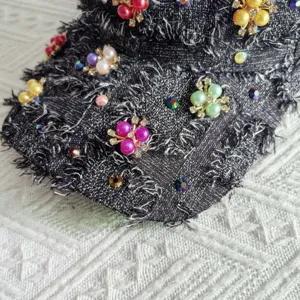 Primo piano dei dettagli del berretto con perle e strass raffigurante decorazione floreale.