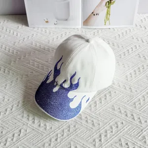 Detailed view of white baseball cap decorated with shiny blue rhinestone flames for streetwear.
