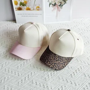 Detail view of two stylish color-block baseball caps featuring pink and leopard print brims.