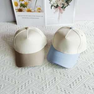 Detail view of two color-blocked five-panel baseball caps in khaki and light blue brim.