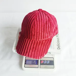 Red corduroy baseball hat detail view showing fine fabric texture and weight display.