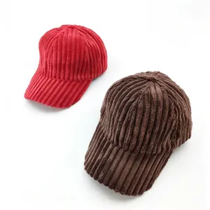 Detailed shot of two thick corduroy baseball caps in red and brown, showing soft fabric texture.