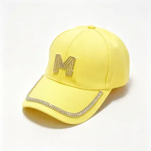 Yellow baseball cap detail featuring a dazzling rhinestone M logo and sparkling brim crystals.