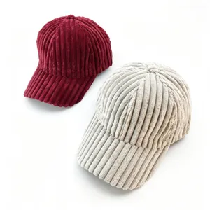 Detailed close-up view of thick corduroy baseball caps in wine red and beige colors, winter style.