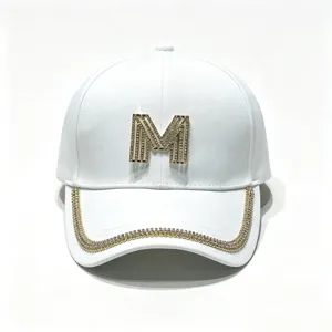 Close up of white baseball cap with rhinestone M logo and glittering crystal brim trim.