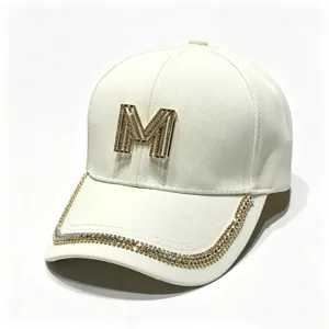 Stylish white baseball cap with metallic M logo and rhinestone brim trim, casual sun hat.