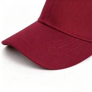 Gros plan détaillé de la visière de casquette en coton rouge foncé avec coutures.
