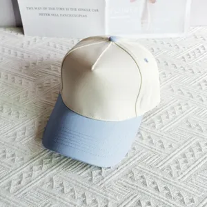 Close-up detail view of a stylish two-tone panel baseball cap in white and light blue cotton.