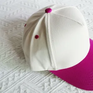 Closeup of a solid white five-panel baseball cap with hot pink brim and top button detail.