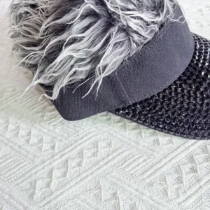Detail view of stylish rhinestone wig visor hat, black brim with sparkling crystals and gray hair.