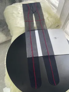 Close-up detail of sexy black pantyhose featuring striking red seam lines for a unique fashion look.