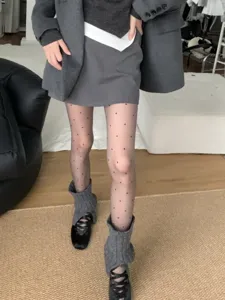 Close-up detail view of women fashion outfit with sheer polka dot tights, skirt and socks.