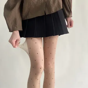 Gros plan détaillant l'élasticité élevée et le motif à pois transparent de la collant.