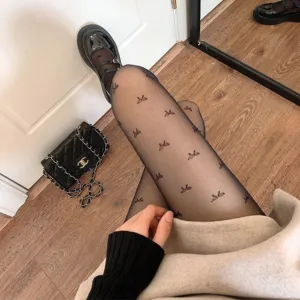 Sheer black jacquard pantyhose with delicate bow pattern, ultra-thin sexy women hosiery detail.