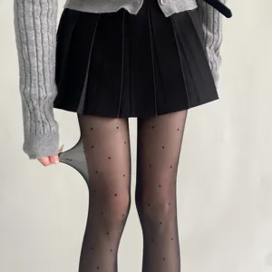 Gros plan sur des collants noirs transparents à pois, matière extensible et douce.