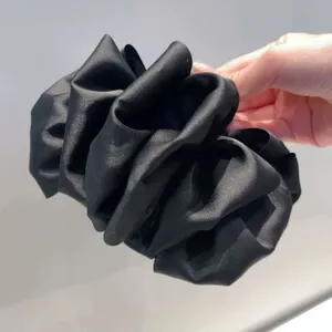Close-up detail of the black satin fluffy hair scrunchie, soft texture and voluminous look.
