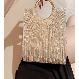 Dettaglio borsa da sera con strass scintillanti, manico tondo dorato e strisce di cristallo.