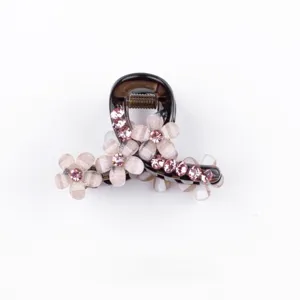 Vista ravvicinata dettagliata del dolce fermaglio per capelli a fiore con strass rosa brillanti.