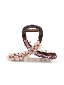 Vista di dettaglio di un elegante mollettone floreale rosa, accessorio con strass.