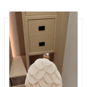Detalle de bolso de noche de perlas elegante, diseño acolchado y cierre dorado.