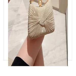 Shimmering metallic gold clutch bag detail, elegant pleated design with pearl clasp.