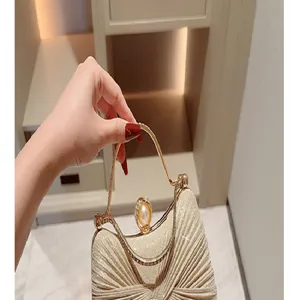 Gold glitter evening clutch bag detail, elegant metal handle and pearl clasp design.