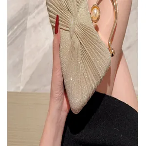 Detailed view of the luxury gold glitter pleated evening clutch bag with elegant pearl handle.