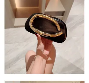 Elegant black evening clutch bag with unique gold metallic handle, luxury design for parties.