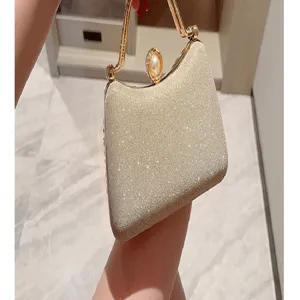 Shimmery gold evening clutch bag with metal handle and pearl clasp for party and wedding.