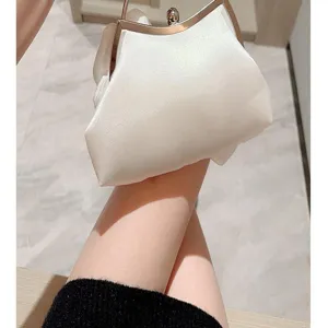 Close-up view of a white satin evening clutch bag with elegant metal frame and handle.