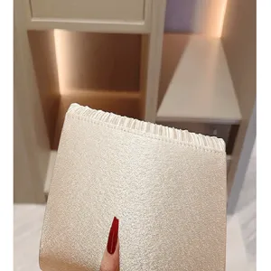 Close-up view of shimmering gold evening clutch bag showcasing fine glitter fabric and elegant texture.