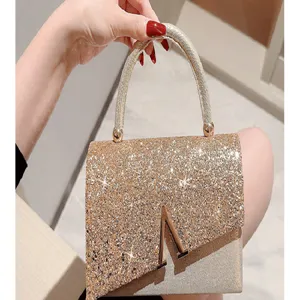 Shining gold evening bag with metallic V clasp and sparkling glitter design for party dress.