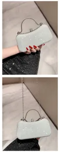 Detail van glanzende zilveren avondtas met metalen handvat, strass slot en ketting.