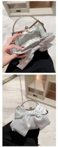 Elegante witte satijnen avondtas met strik, handvat van metaal en ketting voor bruiloften.