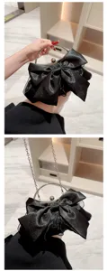 Zwarte satin avondtas clutch met grote strik, metalen ronde handgreep en kettingriem details.