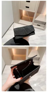 Detailed view of the black glitter evening clutch bag showing its interior structure and chain.