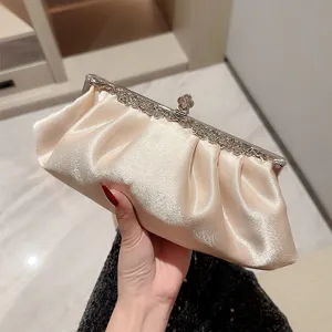 Elegant champagne satin evening clutch bag with ornate metal frame for women banquet.