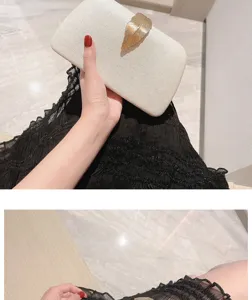 Elegant white evening clutch bag with gold leaf clasp, perfect for parties and formal events.