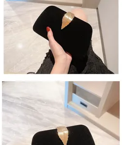 Detail shot of black velvet evening clutch featuring an elegant gold leaf metal clasp and texture.